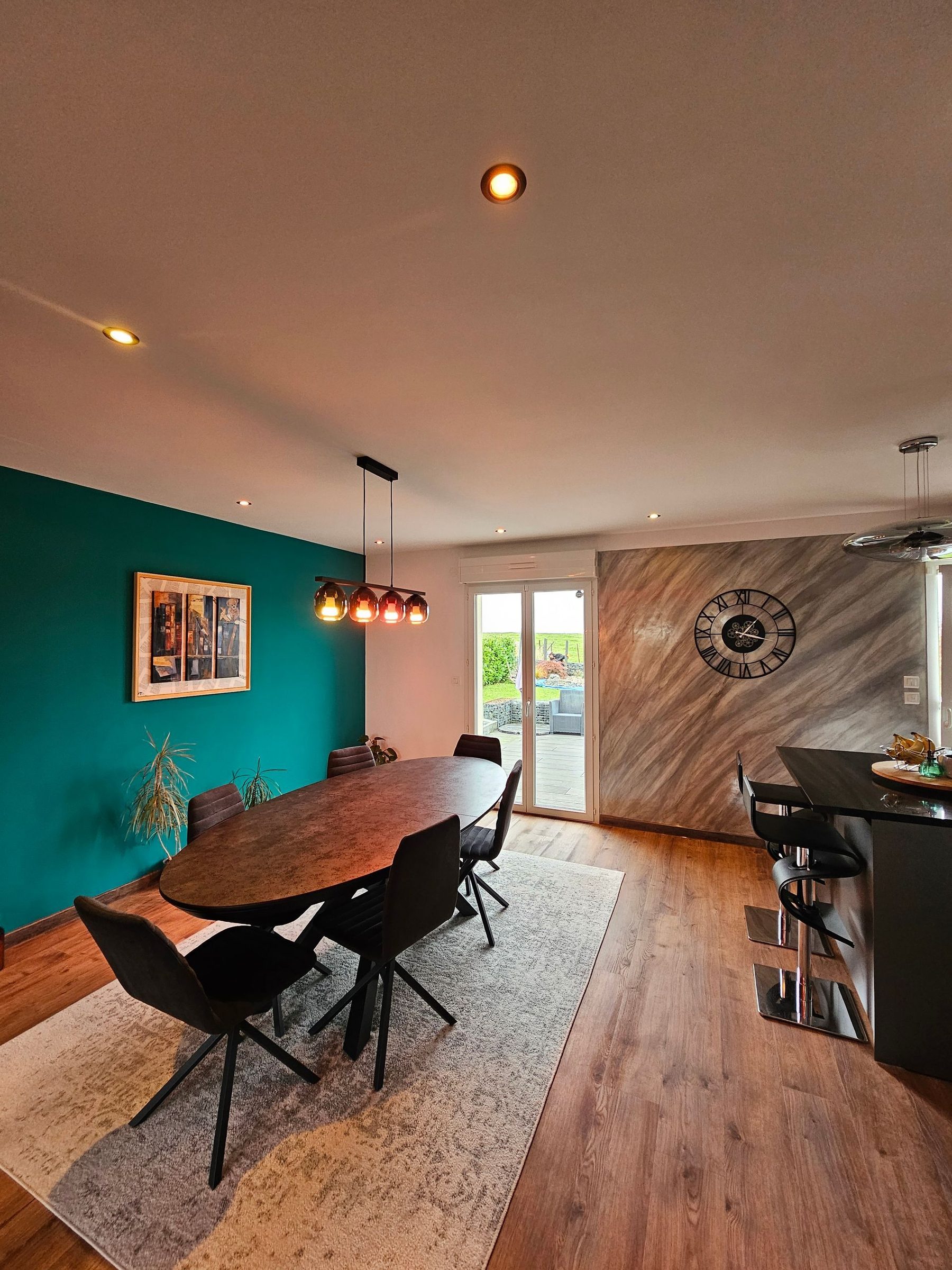 Salle à manger avec un mur bleu canard et un mur en enduit décoratif métallique, réalisés par France Renov Home
