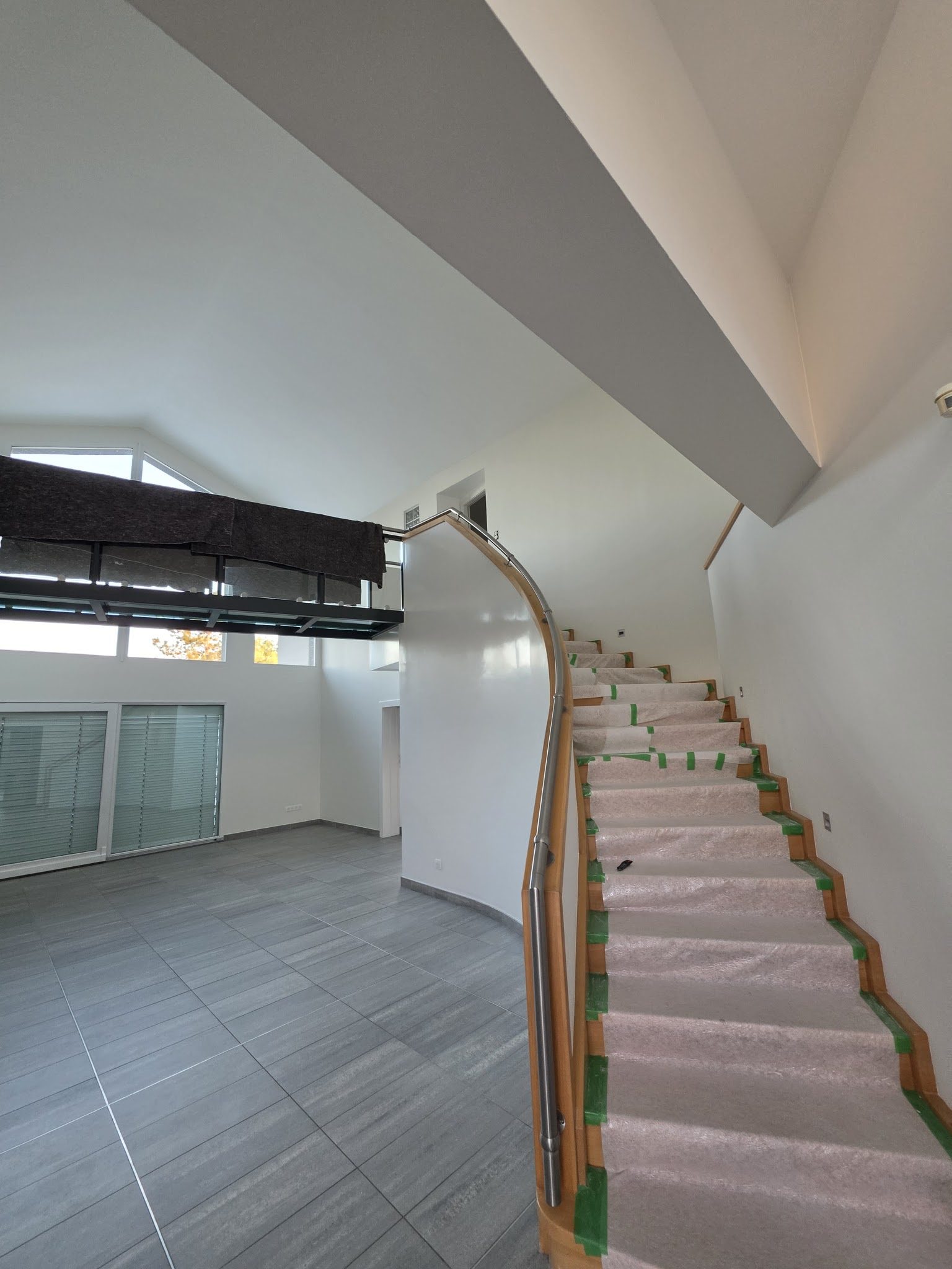 Pièce en double hauteur, rampants et murs peints en blanc, escalier protégé