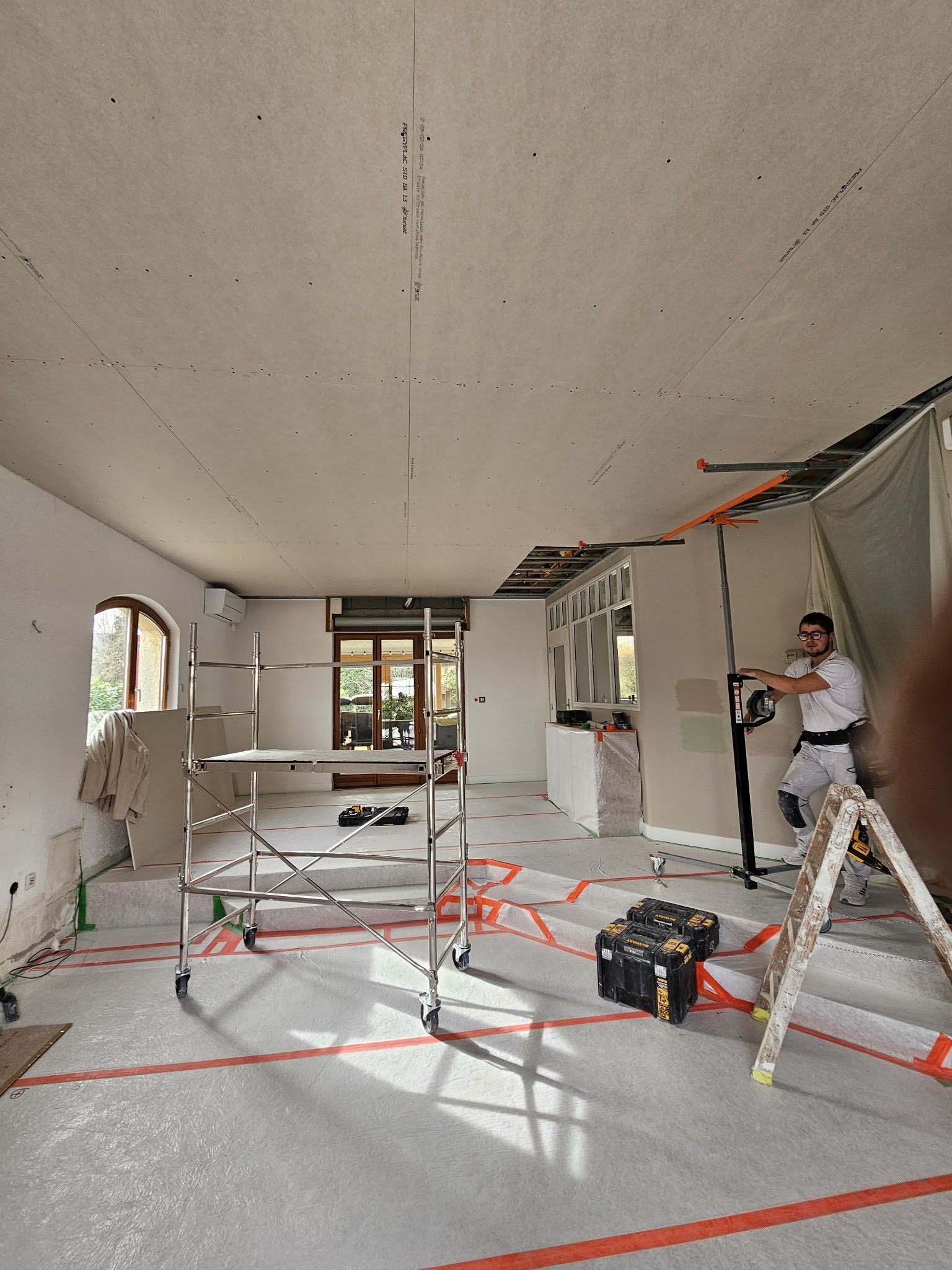 Plafond en plaques de plâtre monté au lève-plaque, sols protégés